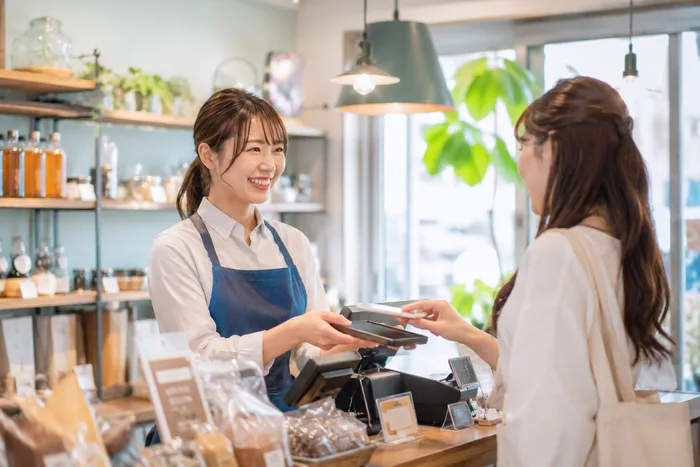 雑貨店のレジでスタッフが笑顔で接客する様子